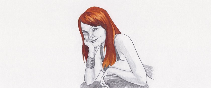 Woman with long red hair sits in her wheelchair, leaning her chin on one hand and smiling